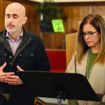 Two people standing and speaking at a lectern in a church setting, focusing on reading or delivering a message.