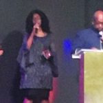 Church choir and speaker on stage with microphones during a live performance or event.