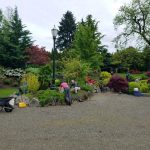 Community volunteers gardening in a landscaped park area with vibrant flowers and trees.