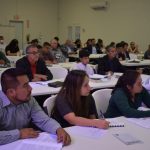 People attending a seminar, focused on taking notes in a conference room setting.