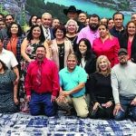 Large group of people smiling and posing together indoors at an event.