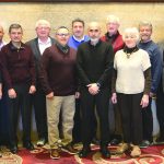 Group of fourteen people standing indoors, posing for a team photo.