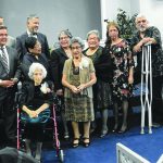 A diverse group of people at a church event, standing and smiling together on a blue-carpeted stage.