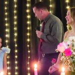 Father-daughter dance event with fairy lights and flowers, featuring a girl in a blue dress and smiling guests.