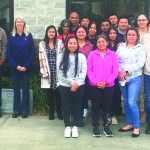 A diverse group of people standing together outside a building, showing community and unity.