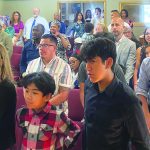 A diverse group of people attentively gathered in a church setting, observing a ceremony.