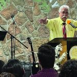 Pastor delivering a sermon with a translator, church setting, microphones, podium, audience listening attentively.