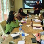 Team planning meeting for Youth Camp 2023, with a presenter and attendees around a conference table.