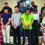 Group of people standing together in prayer during a community gathering at a church service.