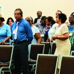 People attending a conference standing in rows, dressed in formal and colorful clothing.
