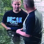 Two people standing in water, engaged in a meaningful conversation.