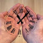Hands holding a transparent clock with Roman numerals, symbolizing time management and care.