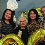 Family celebrating a birthday with golden balloons, posing happily in festive attire.